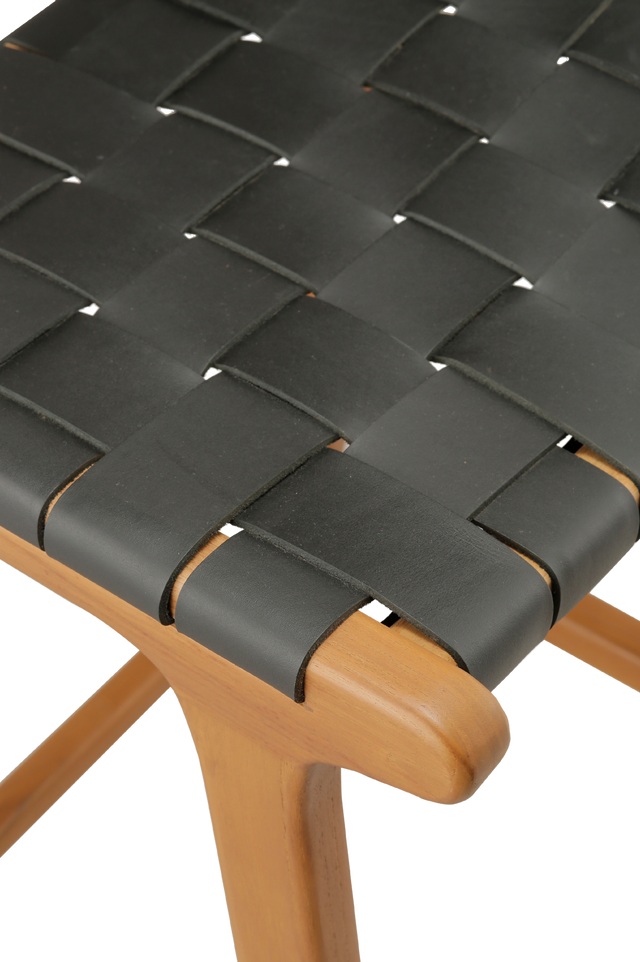 close up of the seat. A wooden counter stool with a woven black leather seat and back, shown against a transparent background.