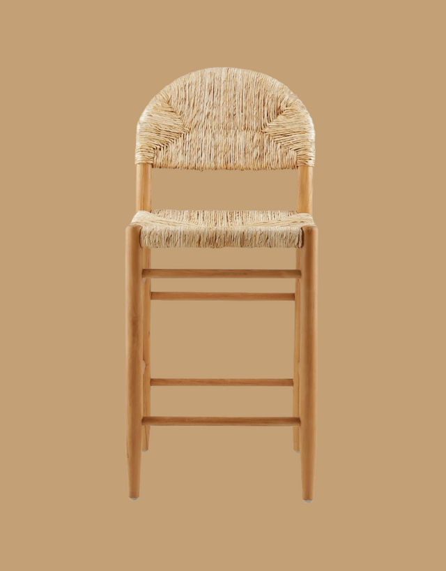 A rustic counter stool featuring a woven natural rattan seat and backrest with an arched design. The stool has a sturdy wooden frame in a light finish, complete with footrests for added comfort and support. front view