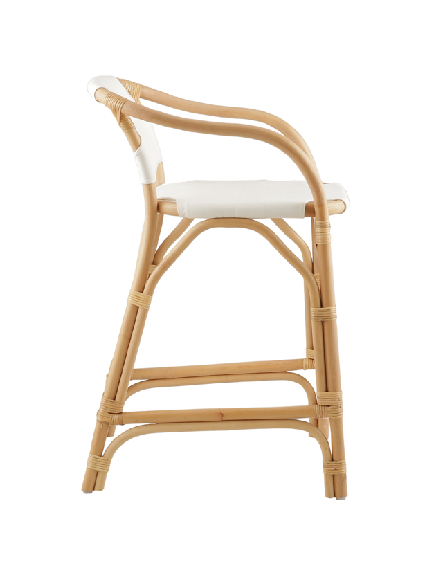 Side View. A natural rattan-style counter stool with a curved frame, white padded seat and back, and woven accents, shown against a transparent background.