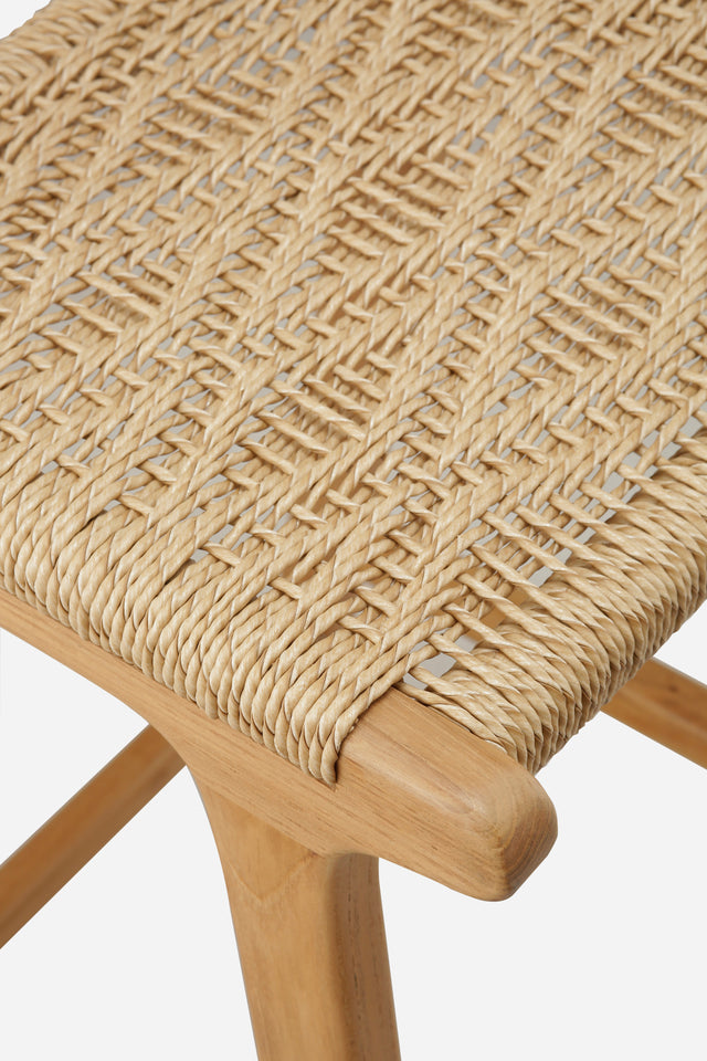 Close up of the weaved seat. counter stool with a woven rattan seat and backrest. The backrest features a square woven pattern, with the rattan weaving arranged in a grid-like formation. The seat is woven with a slightly curved design, offering a comfortable and stylish look.