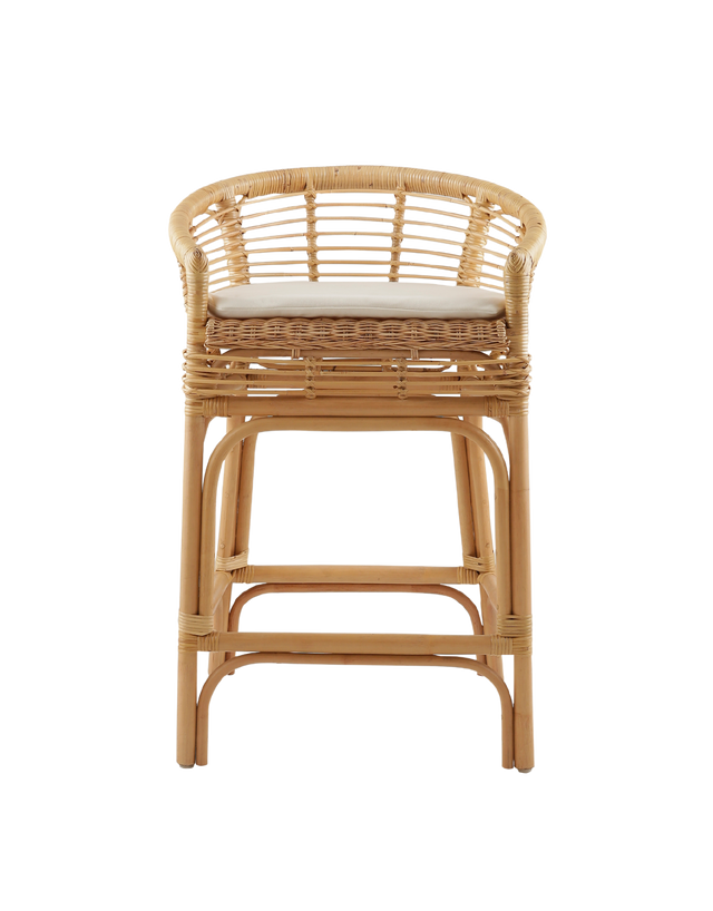 comfortable counter stool made from rattan, featuring a woven seat and backrest with armrests. The stool has a cushioned seat for added comfort and a natural rattan frame with intricate weaving. Its relaxed yet stylish design makes it a perfect fit for modern or coastal-inspired interiors.