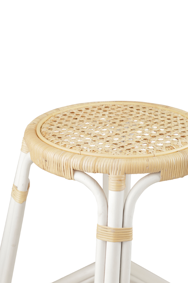 Close up of materials. A rattan counter stool with a round woven seat and white frame accented with natural rattan bindings, shown against a transparent background.